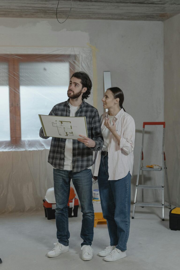 A couple reviews floor plans during a home renovation, surrounded by tools.